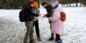 Three individuals in winter attire standing together in a snowy landscape, smiling and enjoying the winter weather.